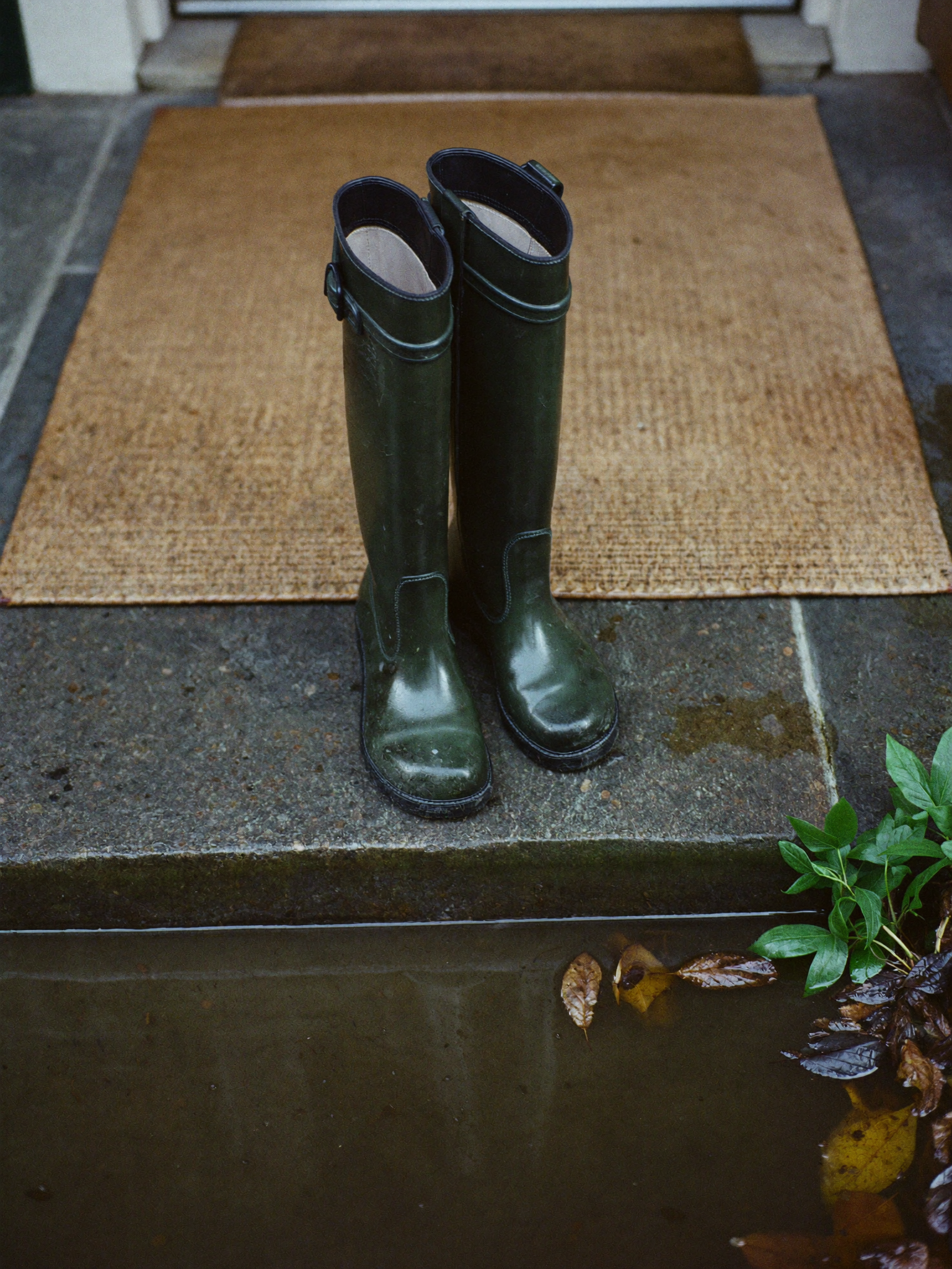 Muddy green wellington boots on a stone doorstep
