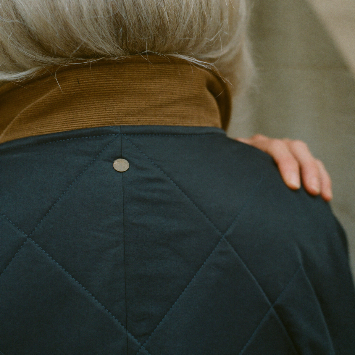 Close detail of a corduroy collar and diamond quilting on a navy country jacket